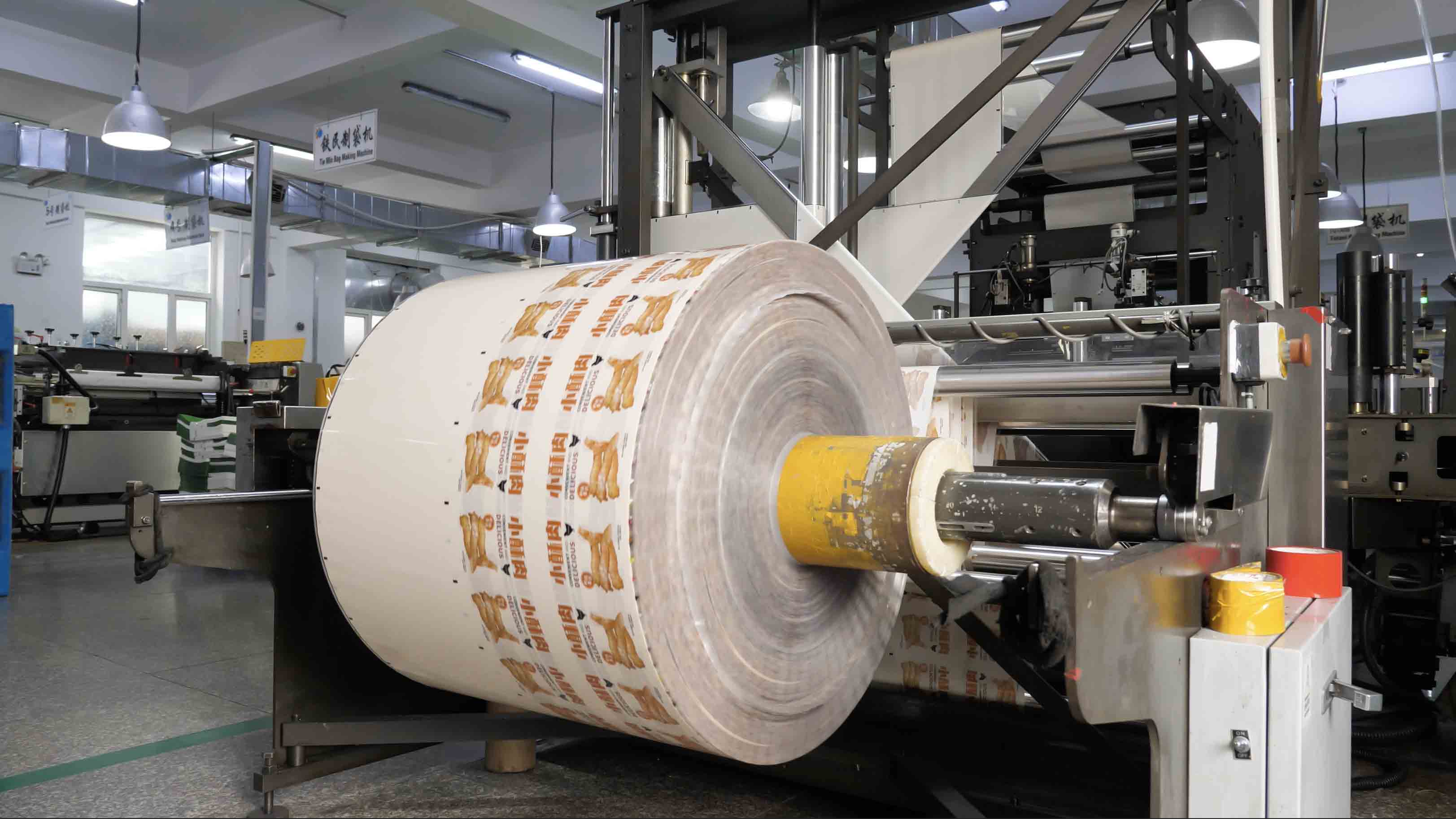 Real printed flexible packaging film roll on a converting machine.