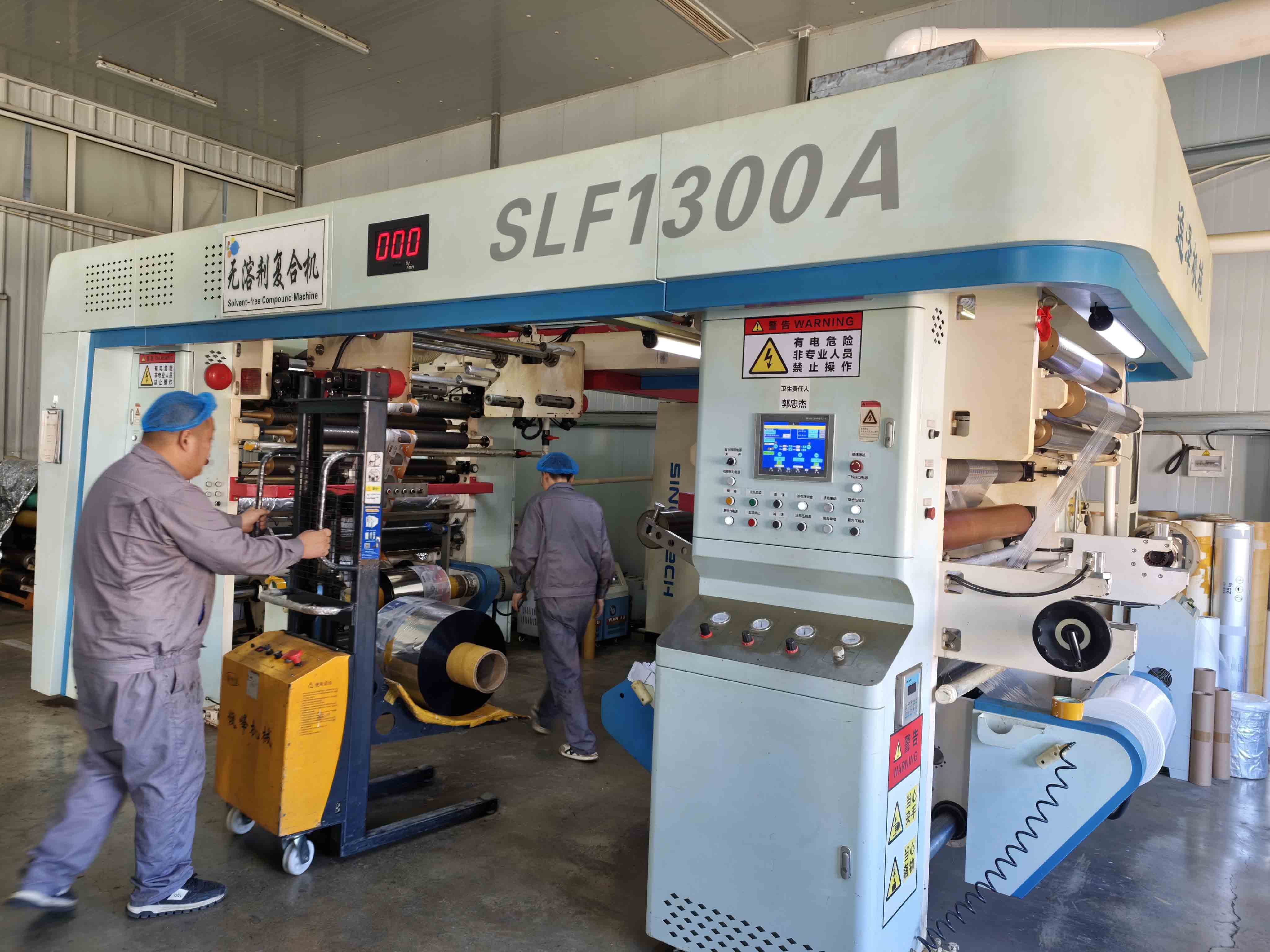 Operators working at Mylarbag's solvent-free film lamination machine.
