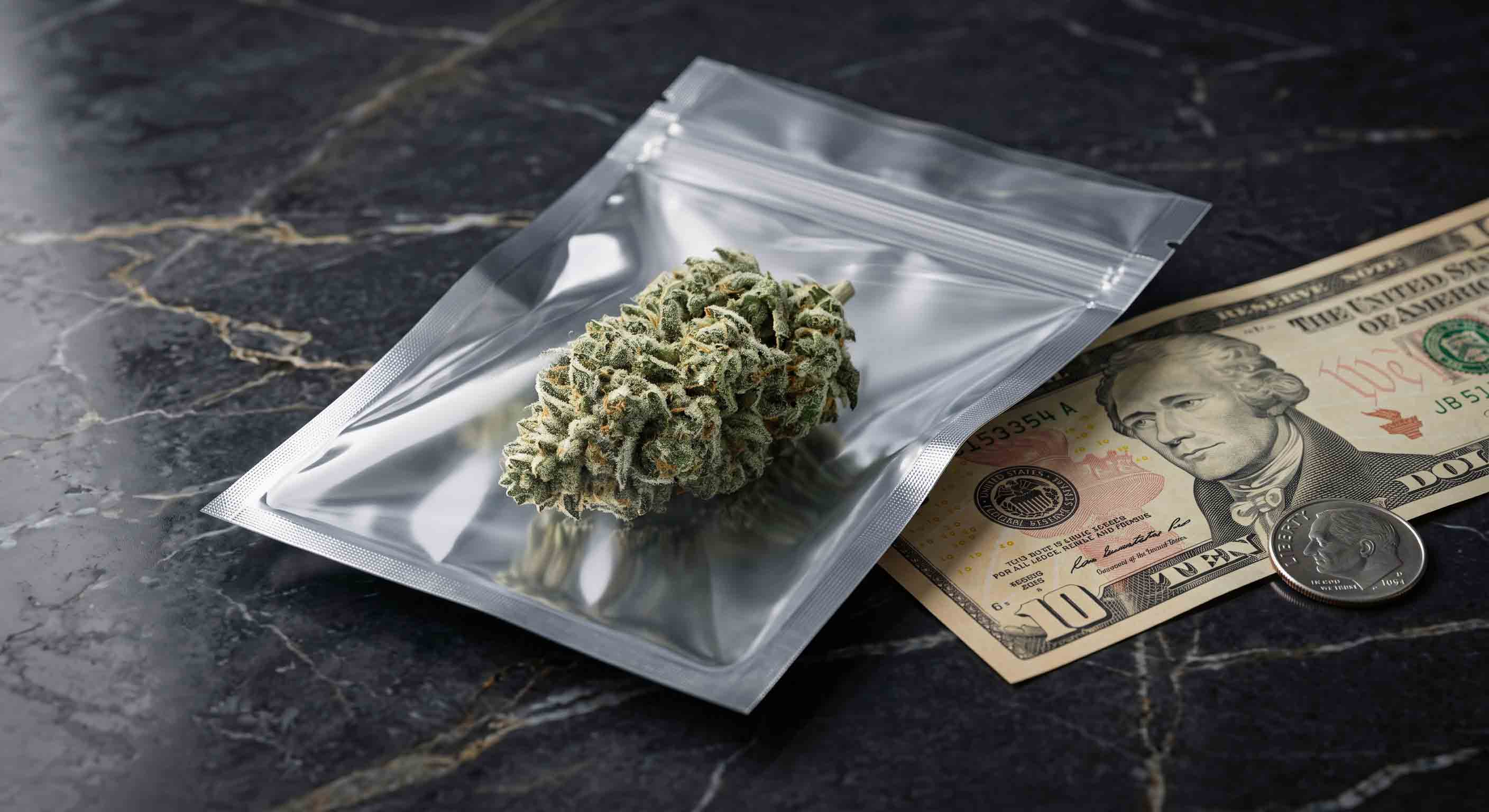 A 1 gram dime bag of weed inside a small pouch next to a 10 dollar bill.